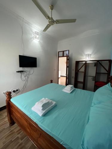 a bedroom with a bed with blue sheets and a television at Amos House in Kendwa