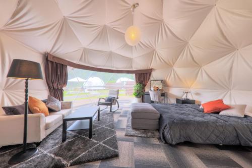 a bedroom with a tent with a bed and a couch at Glamping Resort Varie in Fujikawaguchiko