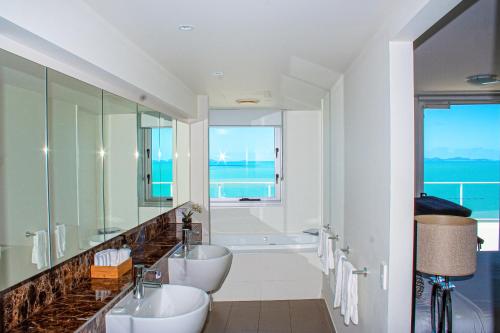 a bathroom with two sinks and a tub and a window at Oshen Holiday Apartments Yeppoon in Yeppoon