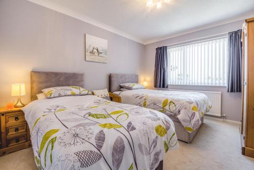 a bedroom with two beds and a window at Cororion Cottage in Benllech