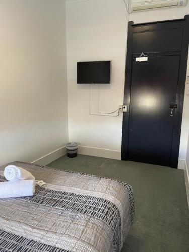 a bedroom with a bed and a tv on the wall at Tattersalls Hotel in Goulburn