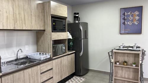 una cucina con frigorifero e lavandino di APTO3 COM AR COND. WIFI E TV SMART a Itapema