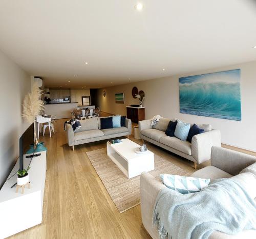 a living room with two couches and a kitchen at Waters Edge Apartment in Rye