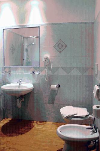 a bathroom with a sink and a toilet and a mirror at Hotel Costa Citara in Ischia