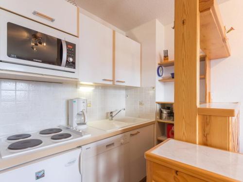 une cuisine avec une cuisinière et un micro-ondes dans l'établissement Appartement rénové, centre station, balcon, coin montagne, proche pistes et commerces - FR-1-275-158, à La Rosière