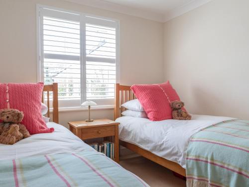 two beds in a bedroom with two teddy bears on them at 5 Thurlestone Beach in Kingsbridge