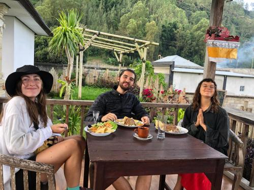 a group of three people sitting at a table with food at Batur Homestay and Lodge in Bangli