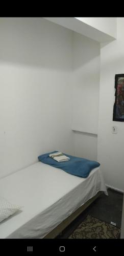 a white bed with a blue blanket on it at Pousada Landus in São Paulo