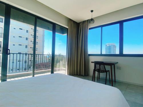 a bedroom with a bed and a desk and large windows at Light House Hostel in Da Nang