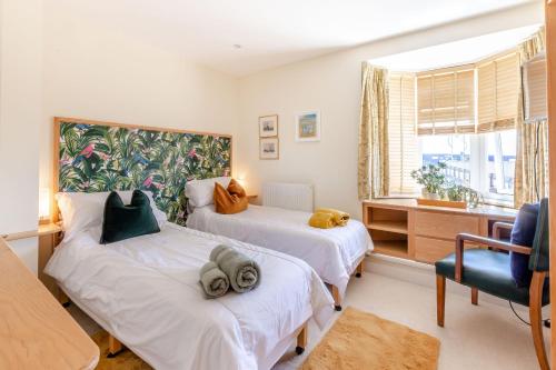 a bedroom with two beds and a chair and a window at Battery House in Portsmouth