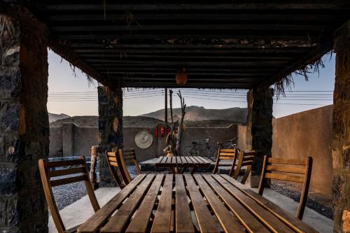 a wooden table and chairs on a porch at Canyon Rest House Jabal Shams in Al Ḩamrāʼ