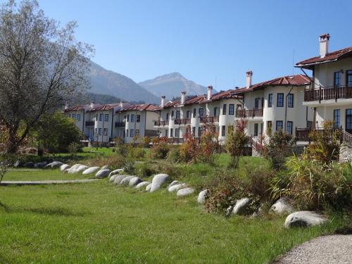 una fila de edificios en un parque con césped y rocas en Pinerose Resort, en Bansko