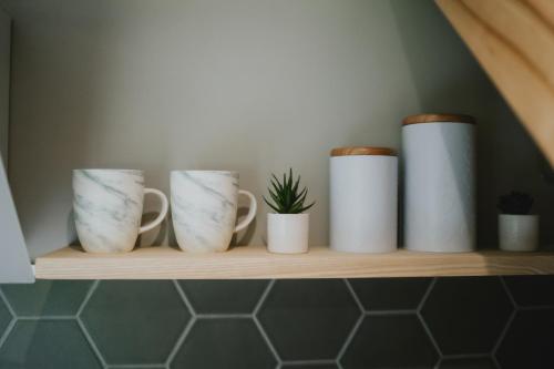 a shelf with five white cups and a plant at Auksi puhkemaja-1 in Auksi