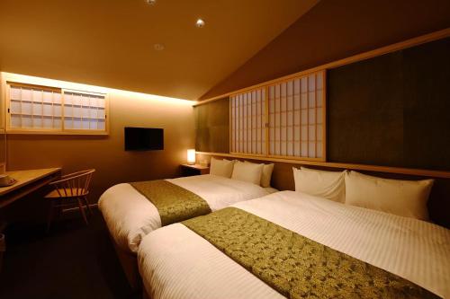 a hotel room with two beds and a desk and window at Kyoyado Heianshiki in Kyoto
