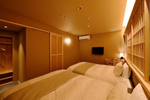 a hotel room with two beds and a television at Kyoyado Heianshiki in Kyoto