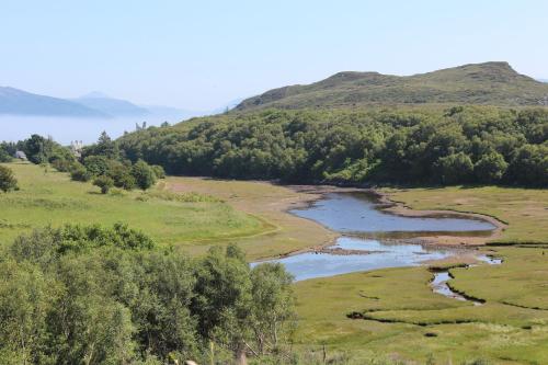a river in a field with a hill in the background at Misty Isle Apartments Ltd - Maol View in Kyleakin