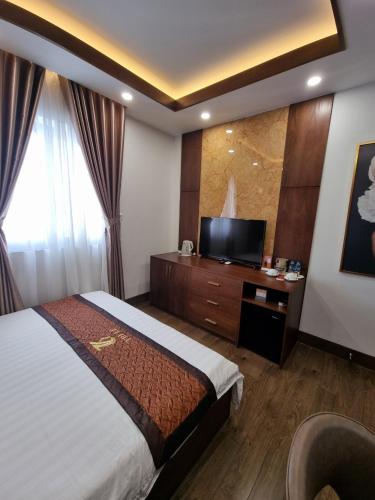 a hotel room with a bed and a flat screen tv at Hotel Trí Lê in Cao Lãnh