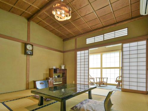 a living room with a table in a room with windows at Irorinoyado Ashina in Aizuwakamatsu