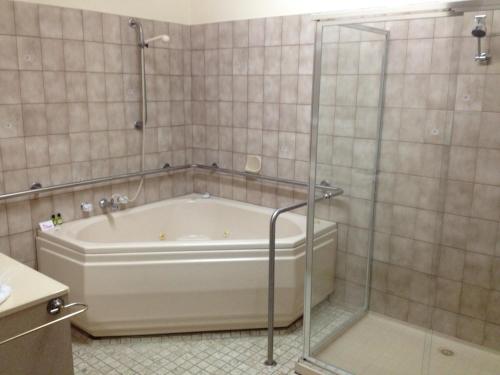 a bath tub with a glass shower in a bathroom at Benalla Apartments in Benalla