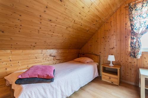 ein Schlafzimmer mit einem Bett in einem Holzzimmer in der Unterkunft Domki i pokoje POD KOGUTEM - kwatery prywatne in Stegna