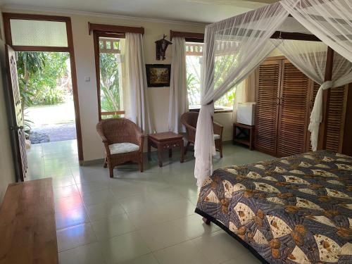 a bedroom with a canopy bed and a table and chairs at Raja Gardens Hotel in Seminyak