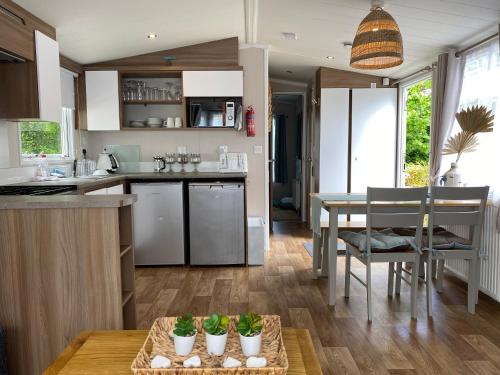 a kitchen and living room with a table and chairs at Cosy, coastal themed Holiday Home, Rockley Park, Poole, Dorset in Poole