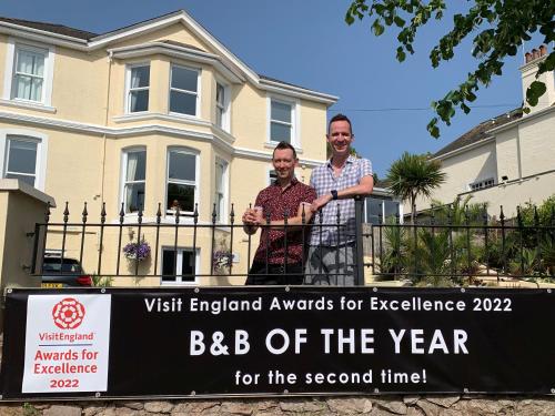 two men standing behind a sign in front of a house at The 25 Boutique B&B - Adults Only in Torquay