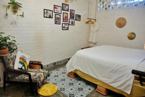 a bedroom with a bed and a chair and pictures on the wall at Mekong Pottery Homestay, Green-Friendly & Boat Tour in Vĩnh Long