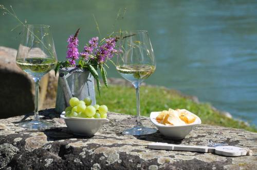 três copos de vinho branco e uma taça de uvas. em La Finestra sul Fiume em Valeggio sul Mincio