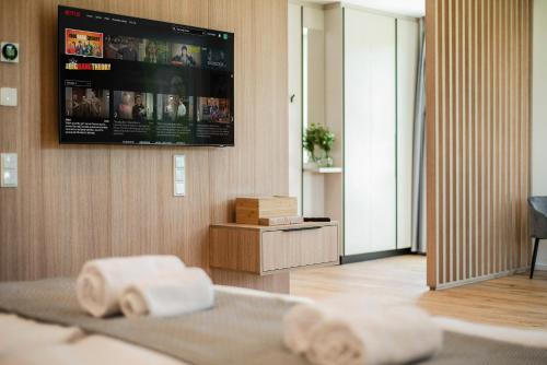 a bedroom with a tv on the wall and two towels at BRIGHT: Rosenheim Aicherpark in Rosenheim