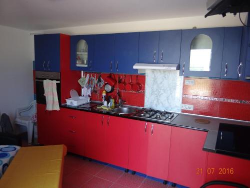 a kitchen with red and blue cabinets and a sink at Casa Marea Neagra in Costinesti