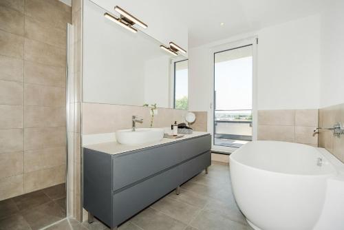 a bathroom with a tub and a sink and a bath tub at BRIGHT: Rosenheim Aicherpark in Rosenheim
