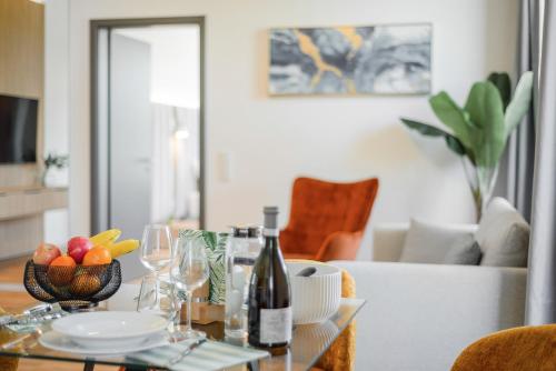 a table with a bottle of wine and a bowl of fruit at BRIGHT: Rosenheim Aicherpark in Rosenheim