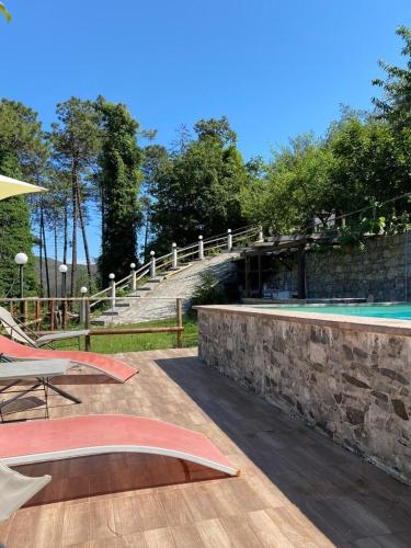 a patio with a stone wall and a swimming pool at Nonno Paco Vacanze in Casarza Ligure