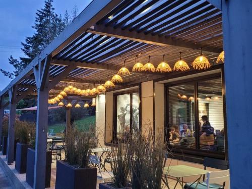 a patio with tables and chairs under a wooden pergola at Hôtel Logis Restaurant La Fontaine in Mantry
