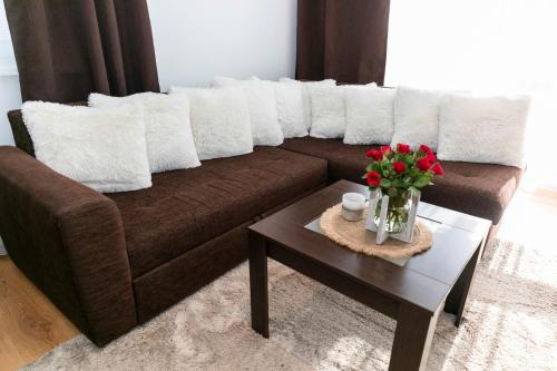 多納瓦利的住宿－ALURE RESIDENCES 4 & 24h self check-in，一张带白色枕头的棕色沙发和一张带鲜花的桌子