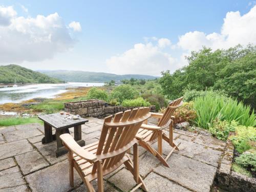 two chairs and a table on a patio overlooking a river at Allt An Dorran in Acharacle