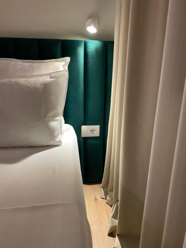 a bed with white pillows and a green wall at Living Studio Apartments in Tirana