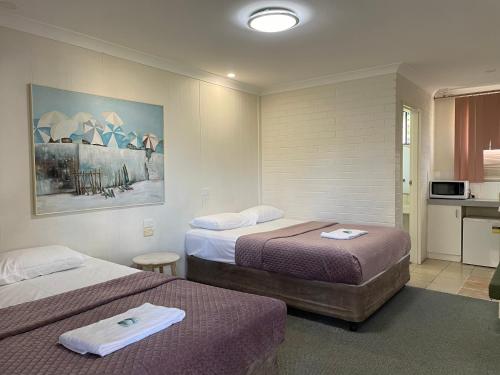 um quarto de hotel com duas camas e uma cozinha em Bananatown Motel em Coffs Harbour