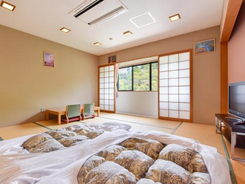 a room with a large bed with a tv and windows at momijigawa onsen in Naka