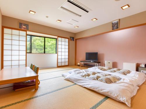 1 dormitorio con 1 cama grande y 1 mesa en momijigawa onsen, en Naka