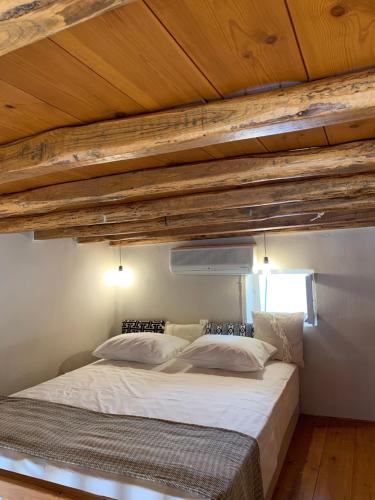 een groot bed in een kamer met houten plafonds bij Ikia Wide Wild Summer House in Kollimpithra