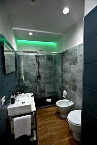 a bathroom with a sink and a shower and a toilet at Kore suites&apartments in Locri