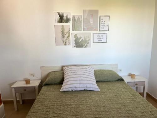 a bedroom with a bed with two tables and pictures on the wall at Villa Calma in Cala en Bosc