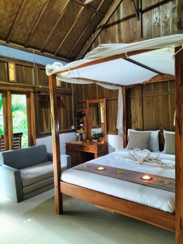 a bedroom with a canopy bed and a couch at Friendly Homestay Lemukih in Singaraja