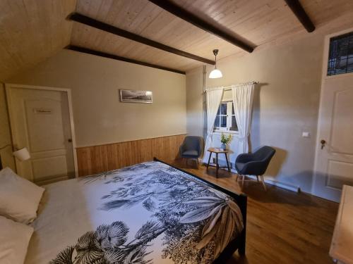 a bedroom with a bed and two chairs in it at B&B de Hugt in Ulrum