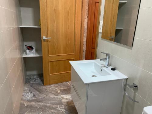 a bathroom with a sink and a wooden door at -Apartamentos Laguna- in Puerto de Mazarrón