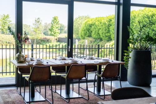 a dining room table with chairs and a large window at La Marquise luxe vakantiehuis in Budel