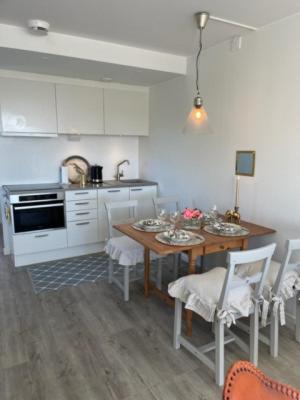 a kitchen with a table and chairs and a kitchen with white cabinets at Lägenhetshotell Varvet in Ellös