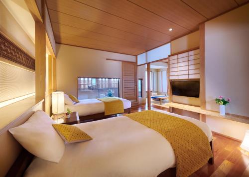 um quarto de hotel com duas camas e uma televisão de ecrã plano em AKARI et KAORI formerly Taizanso em Izu